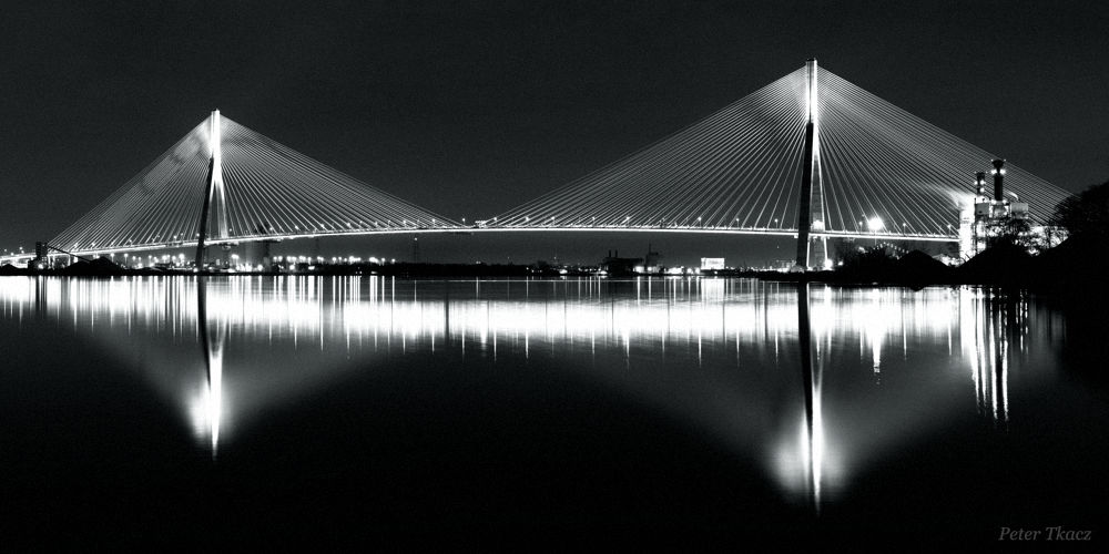 Long exposure night photograph of Gordie Howe International Bridge over Detroit River, noir style, by Peter Tkacz